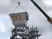 A white observation cabin being installed by crane on top of a modular steel tower with platforms
