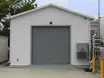 Exterior shot of an outside electrical house with a garage door for easy access and equipment installations