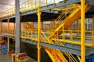 4,843-square-foot steel mezzanine with multiple stair systems, safety-yellow handrails, and pallet access gates.